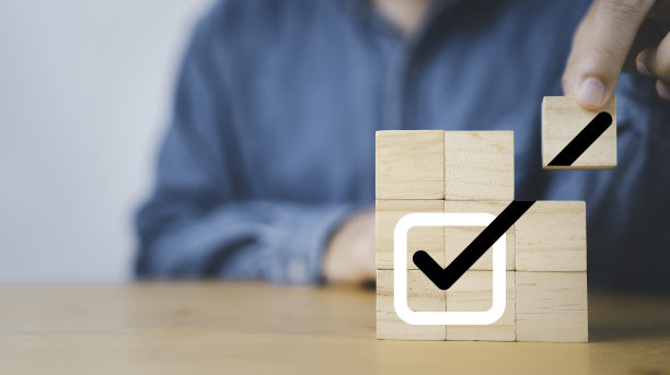 商人在木块立方体上装配正确的打勾标志，以批准商业项目和质量保证概念。图片下载