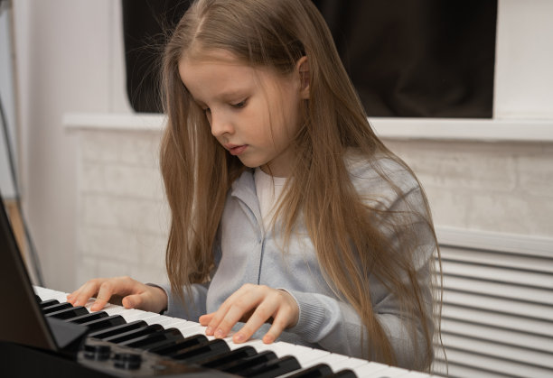 可爱严肃的女孩在弹钢琴。有选择性的重点。音乐教育，一课。图片下载