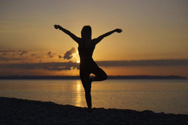 年轻美丽的女人在日出时在海滩上练习图片下载