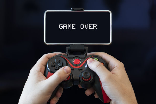 玩家在智能手机上玩游戏。手与操纵杆和电话在黑色背景图片下载