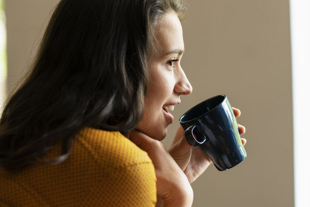 年轻的女商人在办公室喝咖啡。图片下载