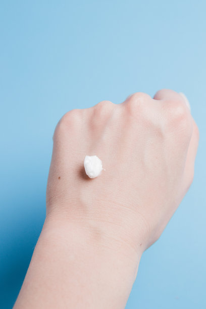 在蓝色背景的女孩手上滴上白色的身体霜图片下载