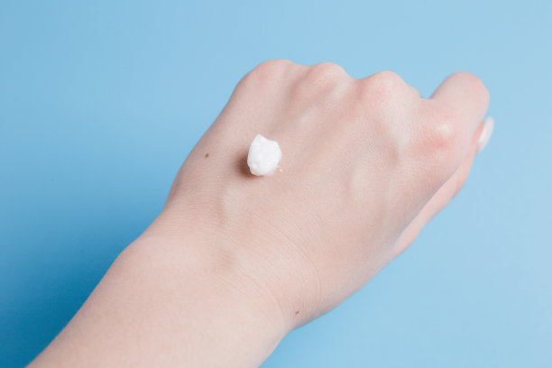 在蓝色背景的女孩手上滴上白色的身体霜图片下载