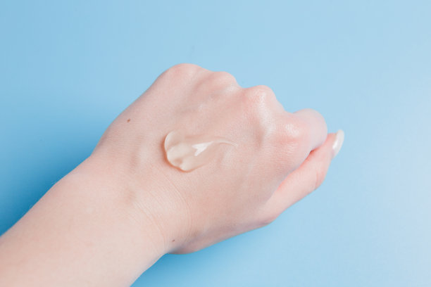 蓝色背景的透明凝胶消毒剂滴在女孩手上图片下载