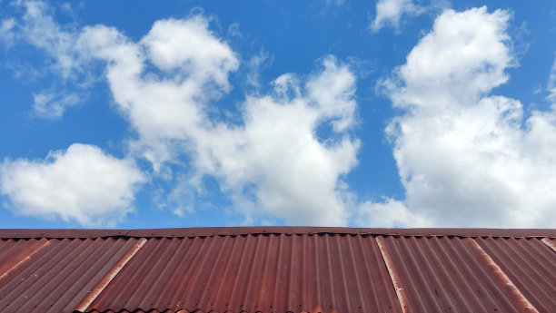 生锈的屋顶纹理与白云和清晰的蓝天背景图片下载