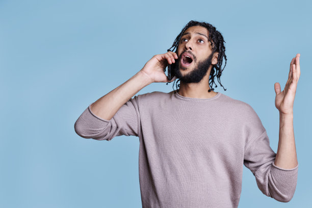 一个阿拉伯人一边用智能手机大声说话，一边打手势图片下载