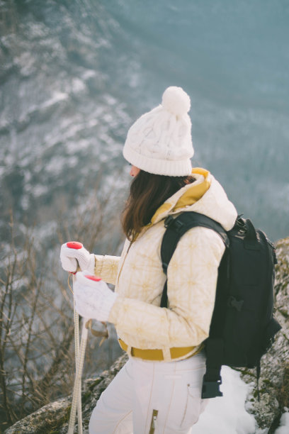 年轻女子背着背包，在美丽的雪山中拄着登山杖散步图片下载