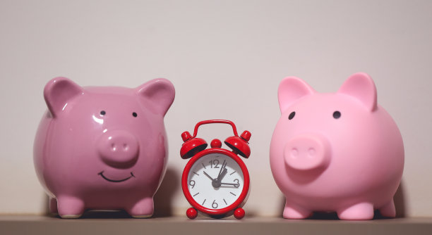 两个储蓄罐和一个红色闹钟。金融的概念。图片下载