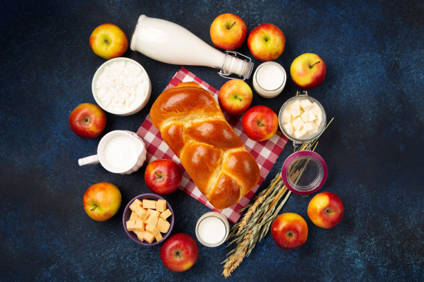 犹太五旬节贺卡。采购产品乳制品，苹果，奶酪，面包，牛奶在蓝色的木制背景。图片下载