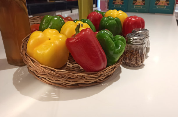 厨房里的竹篮里，黄色、红色和绿色辣椒的选择性对焦照片。图片下载