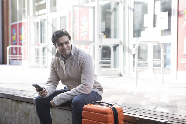 一个拿着手机在火车站外等候的专业人士图片下载