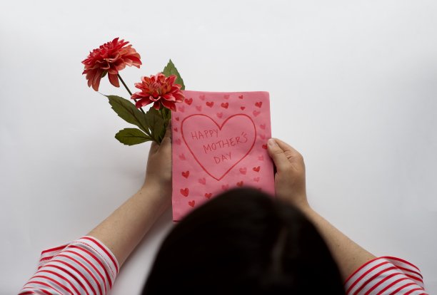 母亲节假期概念。妈妈拿着礼物、鲜花和手工贺卡。母亲节快乐。隔离在白底图片下载