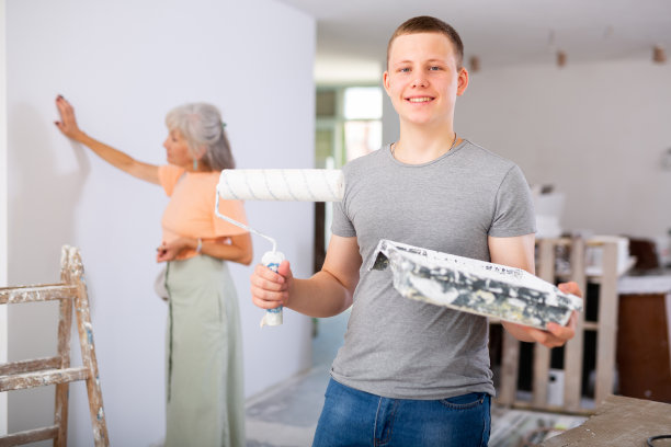 十几岁的男孩在建筑工地拿着油漆滚筒的肖像图片下载