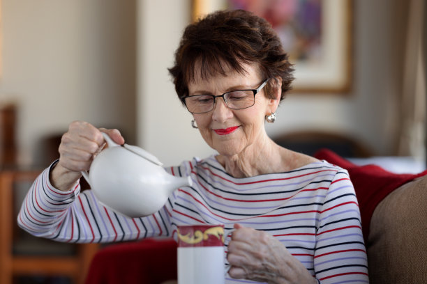 老妇人从茶壶里倒茶图片下载