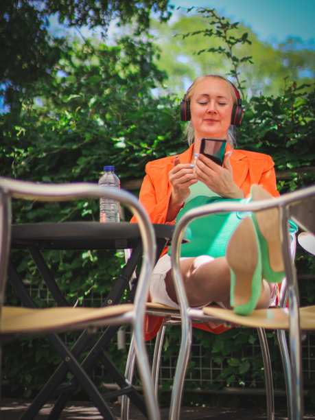 年轻漂亮的白种金发女孩用耳机拿着智能手机听音乐图片下载