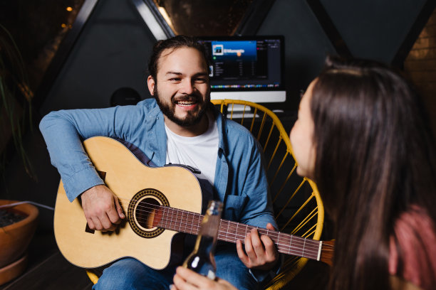 年轻的拉丁夫妇在一个浪漫的约会弹吉他，女朋友和男朋友在墨西哥晚上在家里玩拉丁美洲，西班牙人图片下载