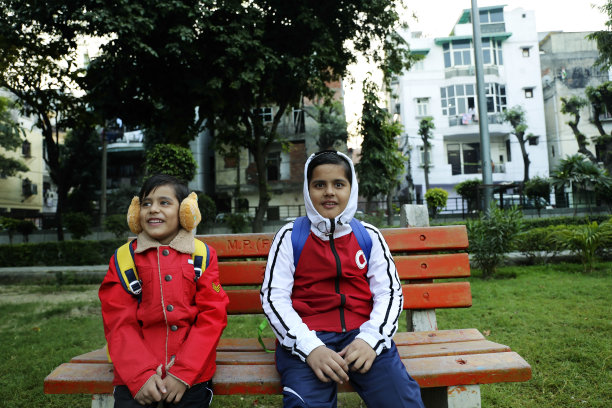 回到学校。背着书包的学生坐在长凳上等校车图片下载