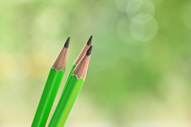 三尖的绿色木制铅笔在模糊的自然背景与散景图片下载