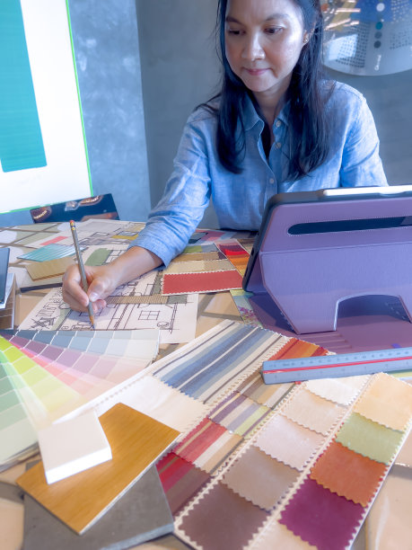 一位女设计师在设计工作室与智能设备和材料样品一起工作。图片下载