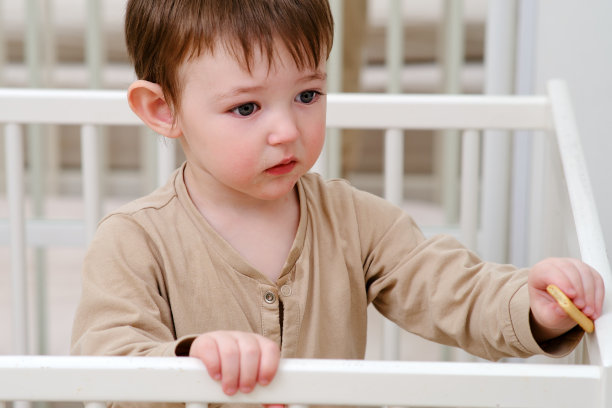 孩子在婴儿床里吃饼干。在床上像在围栏里一样喂婴儿。两岁左右(一岁九个月)图片下载