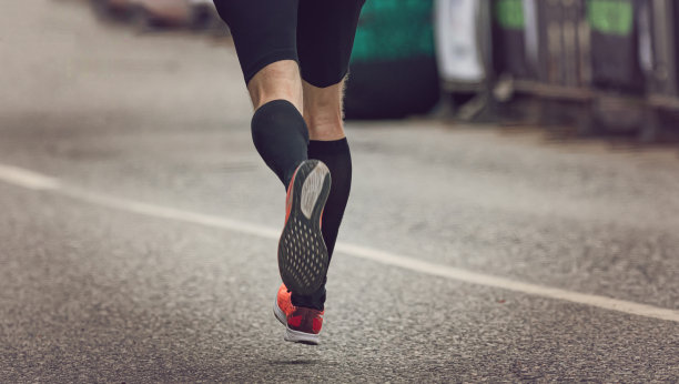 在柏油路上跑马拉松的运动员的腿图片下载