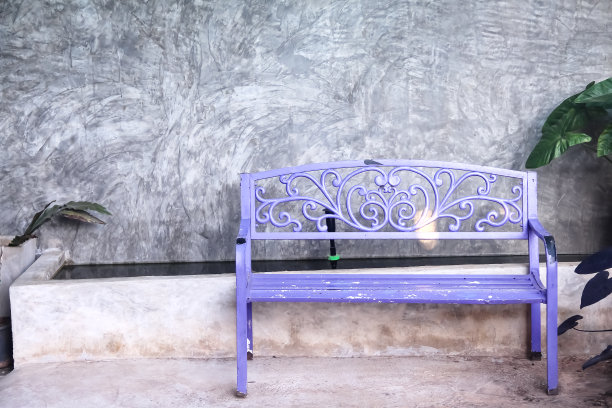 灰色混凝土墙背景上的旧的空白紫色钢凳图片下载