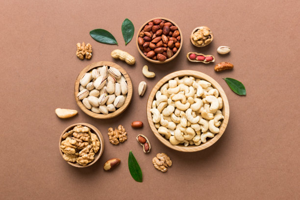 在木碗里混合坚果。在彩色背景上混合各种坚果。开心果、腰果、核桃、榛子、花生和巴西坚果图片下载
