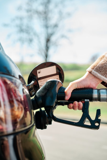 在经济和石油危机时期，一位妇女用手给她的汽车加油的垂直特写照片图片下载