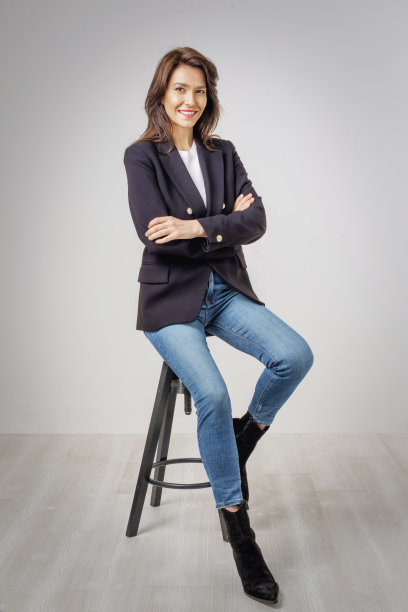 微笑的黑发女人穿着白色背景的运动上衣和牛仔裤图片下载