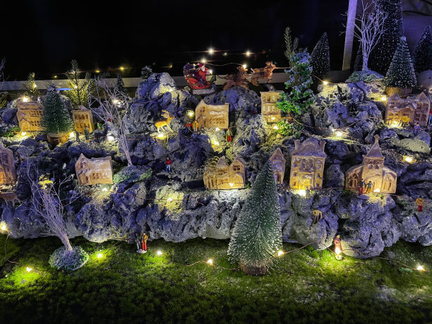 橱柜顶部展示的圣诞村全景图，羊毛雪地上的人造塑料和木制圣诞树，周围是发光的自制木屋和姜饼人，重点放在前景图片下载