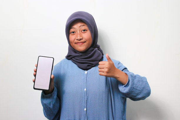 年轻的亚洲女孩戴着头巾，在白色的背景上竖起大拇指。图片下载