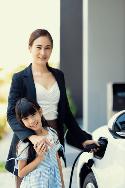 拥有电动汽车和充电站的进步式母女生活方式。图片下载