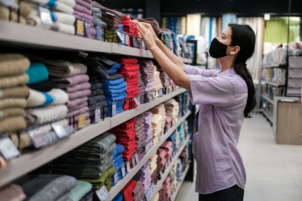 年轻的女顾客在纺织部购物，在家居用品店挑选毛巾。家居装饰和舒适的概念图片下载