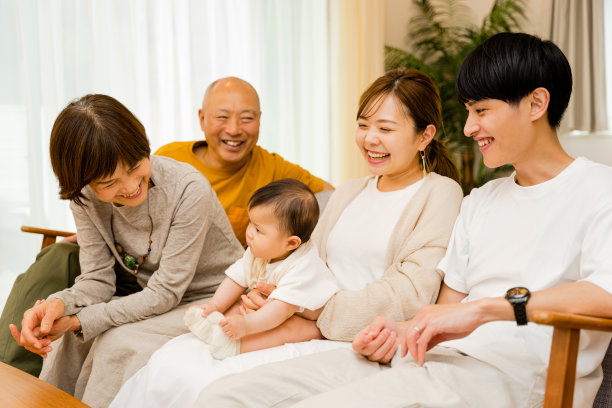 一个0岁的婴儿躺在她母亲的膝盖上，父亲和祖父母照看着她图片下载