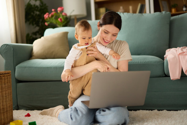可爱的小男孩和他的妈妈坐在客厅的地板上使用笔记本电脑图片下载