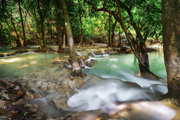 温泉温泉自然浴池被红黄树叶环绕。在秋叶中，瀑布落在许多树叶之间，在秋叶中树叶的颜色变化图片下载