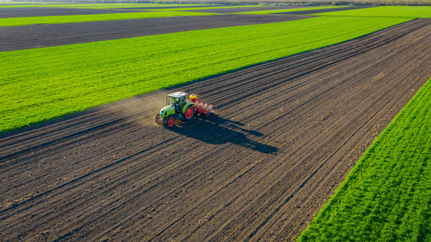 农用拖拉机拖着播种机在农田上空鸟瞰图图片下载