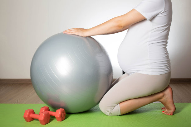 这个女孩在怀孕期间从事普拉提和体育运动。用健身球和哑铃锻炼。女性健康。文本复制空间图片下载