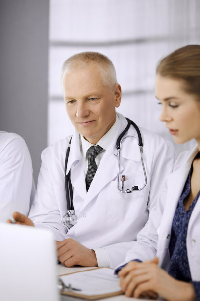 老年医生和他的女同事坐在诊所的工作地点讨论目前的疾病治疗。医院的团队合作。医药保健理念图片下载