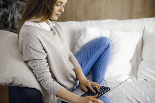 在新冠肺炎隔离期间，坐在舒适的客厅里摆弄笔记本电脑的女商人。冠状病毒大流行期间呆在家里的概念图片下载