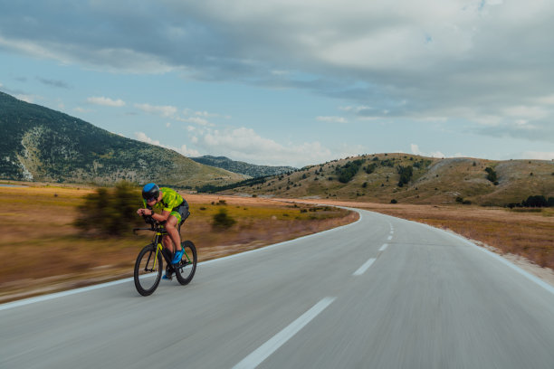 一个穿着运动服、戴着防护头盔骑自行车的铁人三项运动员的全身画像。有选择性的重点图片下载