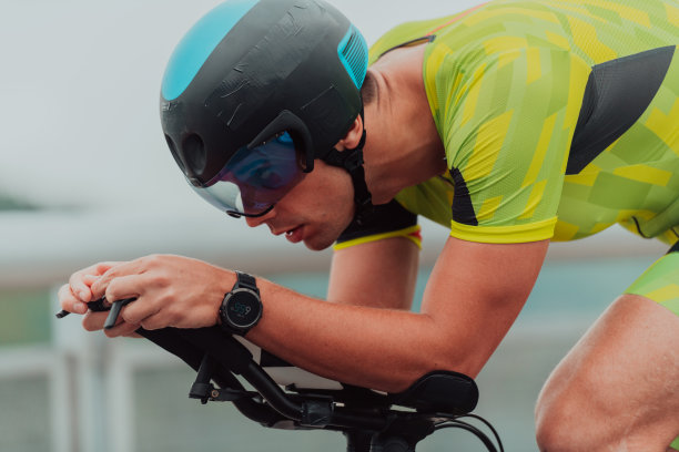 一个穿着运动服、戴着防护头盔骑自行车的铁人三项运动员的特写照片。有选择性的重点图片下载