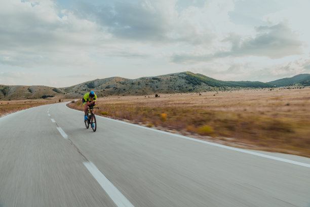 一个穿着运动服、戴着防护头盔骑自行车的铁人三项运动员的全身画像。有选择性的重点图片下载