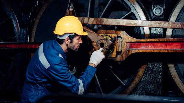 铁路工程师穿着安全制服和安全帽在列车下接受检查。图片下载