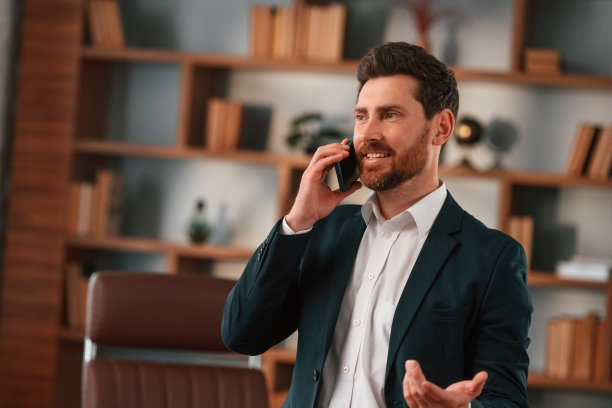 通过电话积极交谈。穿着正装的商人正在室内工作图片下载