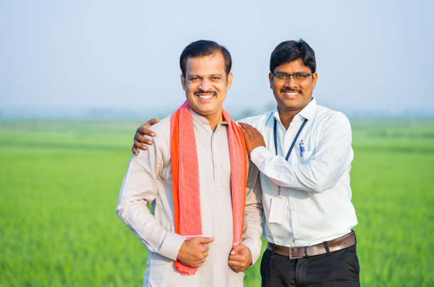 快乐的支持银行家与农村农民站在绿色农田旁边看相机-银行服务，援助和保证的概念图片下载