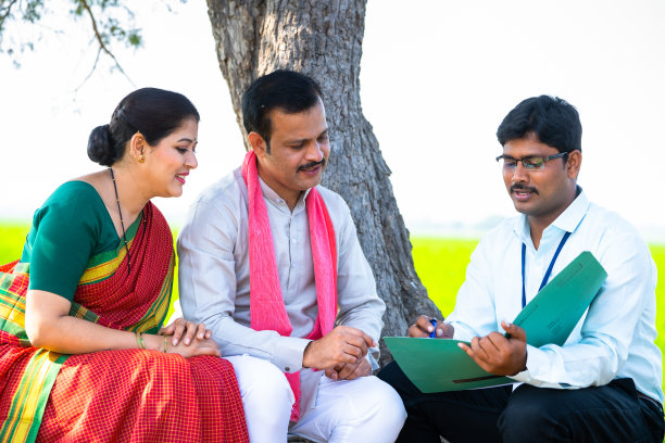 银行家坐在农田上向农村夫妇讲解农业贷款方案——专业概念、银行支持和投资咨询图片下载