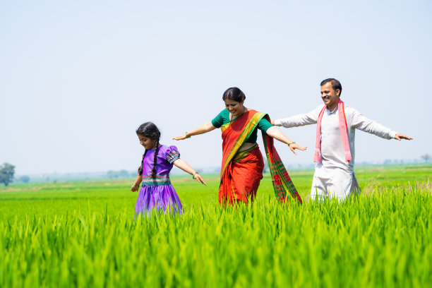 俏皮的快乐乡村农场夫妇带着孩子在绿色的农田里散步，通过平衡真人，家庭纽带和享受的概念图片下载