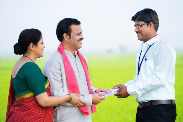 银行印度官员在农田里给农民夫妇钱——金融支持的概念，农业综合企业投资和贷款批准图片下载