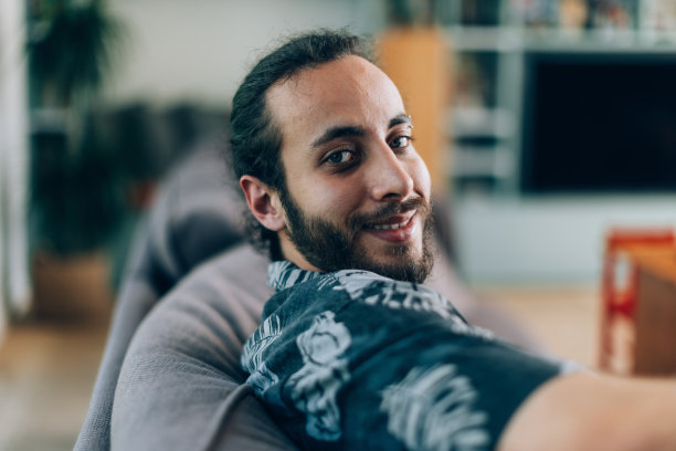 年轻男子坐在家里的沙发上的人像照片图片下载